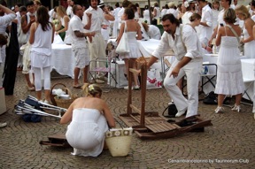 Cena in bianco: persone vestite di bianco a un evento all'aperto. Atmosfera festosa e conviviale.
