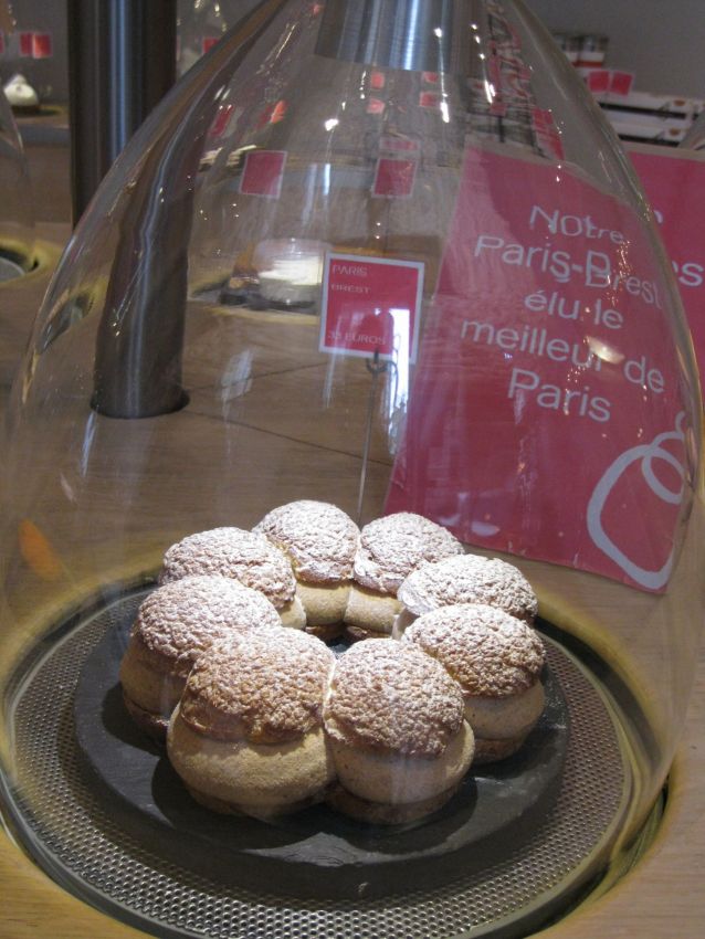 Paris-Brest sotto campana di vetro. Dolce francese con pasta choux e crema al pralinato, spolverato di zucchero a velo.