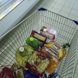 Carrello spesa pieno di alimentari: pasta, olio, snack. Acquisti al supermercato, prodotti alimentari vari.