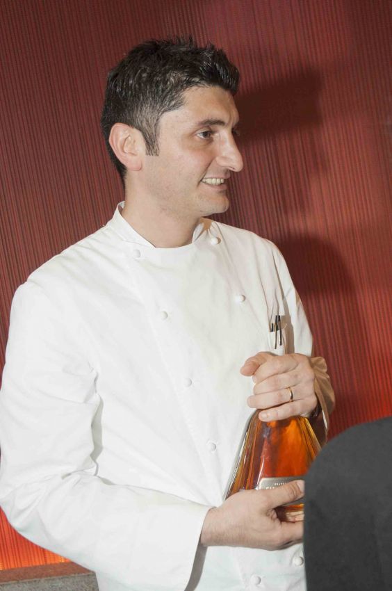 Chef Aprea con bottiglia di liquore. Cucina italiana, chef stellato, alta cucina.