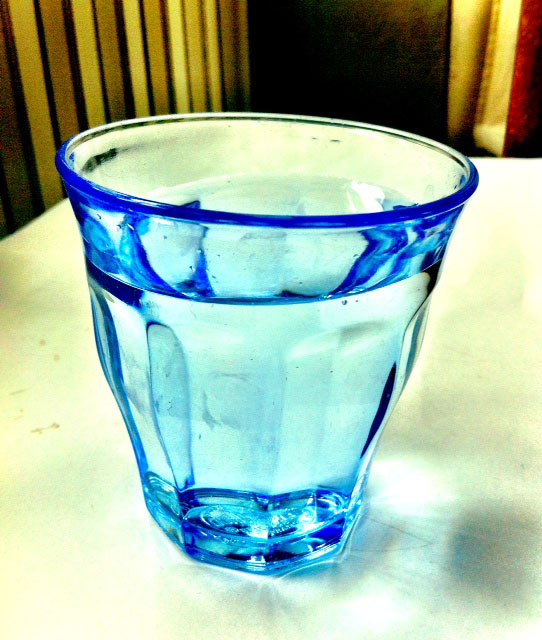Bicchiere d'acqua blu. Acqua potabile in vetro trasparente. Idratazione.