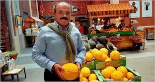 Mercato italiano: uomo con melone giallo. Frutta fresca di stagione in vendita.