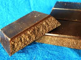 Cioccolato fondente artigianale. Tavolette di cioccolato scuro su sfondo blu. Dolciumi e dessert.