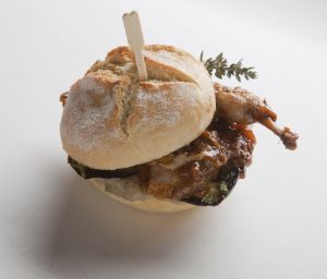 Panino gourmet con quaglia, salsa saporita e erbe aromatiche. Delizioso street food italiano.