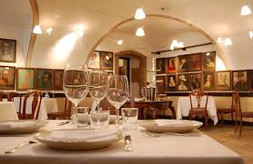 Interno ristorante elegante. Tavolo apparecchiato, calici, quadri. Ristorante di lusso, atmosfera raffinata.