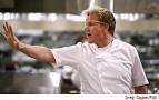 Chef Gordon Ramsay con gesto di stop in cucina. Ristorazione, alta cucina.