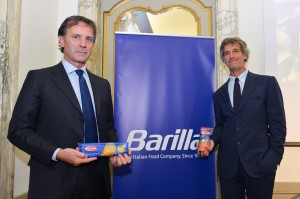 Due uomini in giacca presentano pasta Barilla. Prodotti alimentari italiani, tradizione culinaria, marchio storico.