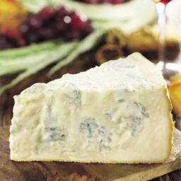 Primo piano di gorgonzola DOP, formaggio erborinato italiano su tagliere di legno.