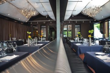 Interno elegante di ristorante. Tavoli apparecchiati, lampadari moderni, atmosfera raffinata.