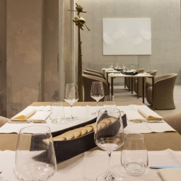 Interno sala ristorante elegante. Tavoli apparecchiati con calici, pane e tovaglioli. Design d'interni raffinato.