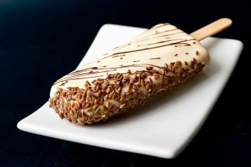 Gelato stecco artigianale. Copertura cioccolato bianco e semi di lino. Dessert estivo goloso.