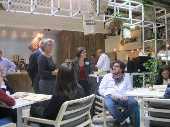 Fiera del caffè: persone a un evento con sacchi di caffè e logo Milani.