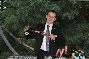 Cameriere versa spumante rosè. Bottiglie di vino e bevande fresche. Evento, festa, celebrazione.