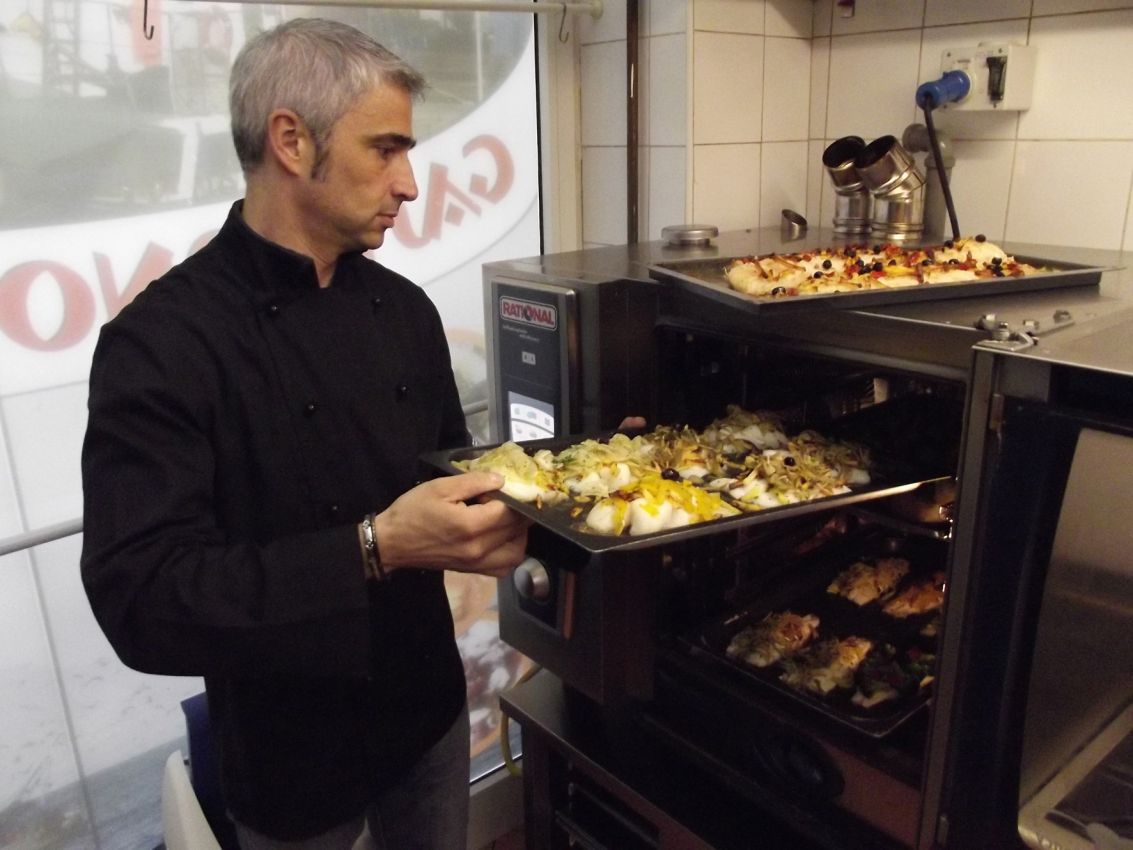 Chef con forno Rational. Vassoi di pizza e pesce cucinati. Cucina professionale.