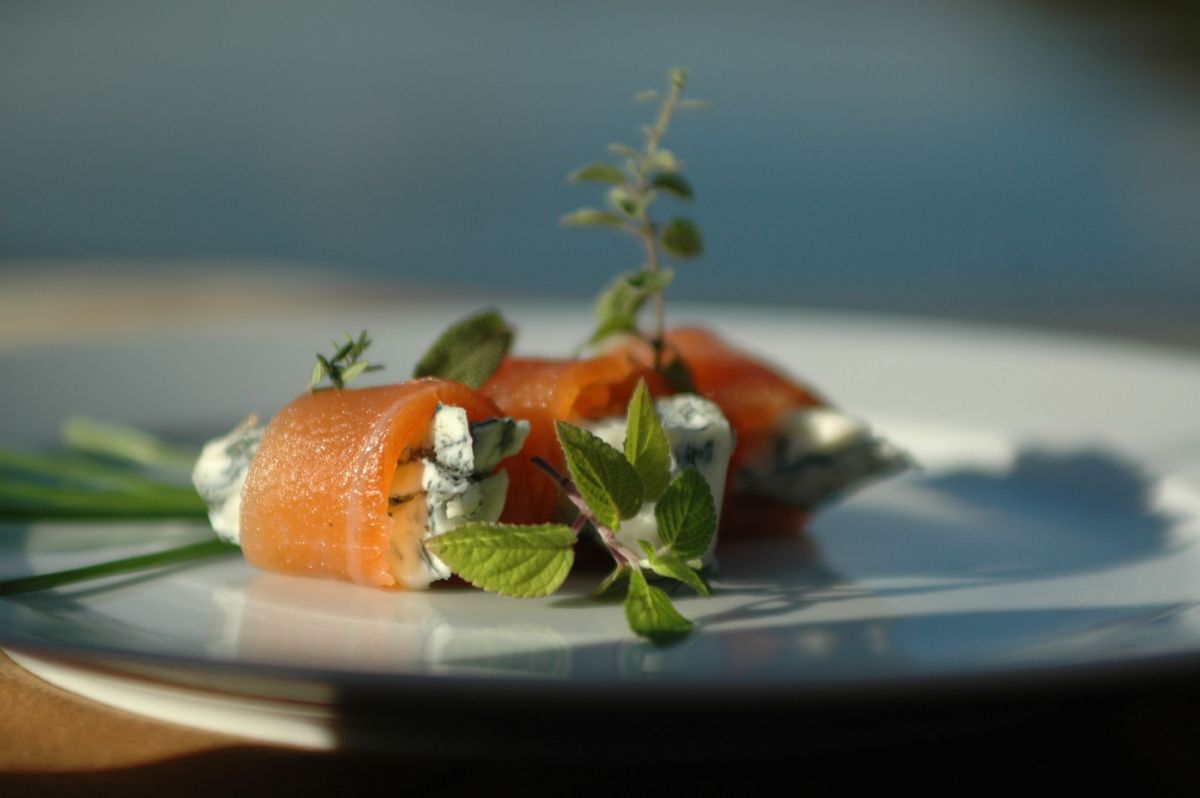 Involtini di salmone marinato con formaggio erborinato e erbe fresche. Antipasto gourmet.