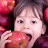 Bambina morde mela rossa. Frutta fresca, alimentazione sana per bambini.