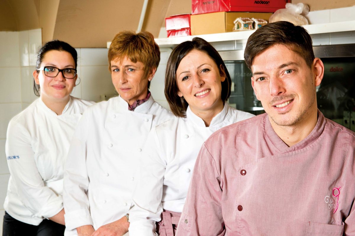 Team di chef sorridenti in cucina. Ristorante, gastronomia, professionisti del cibo, alta cucina.