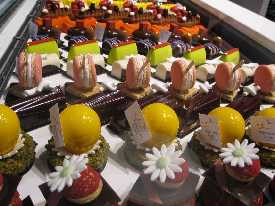 Vetrina di pasticceria francese con macarons, cioccolato e dolci colorati. Delizie artigianali.