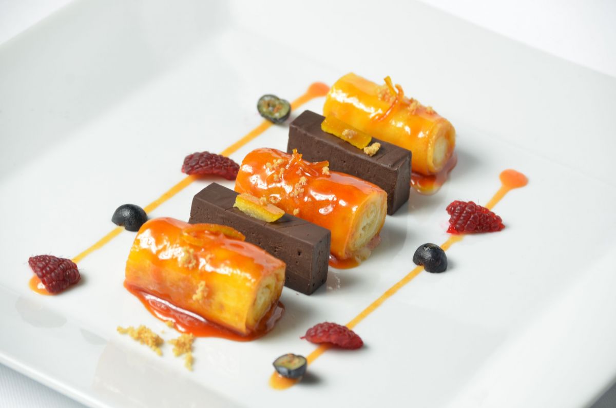 Crespelle farcite con crema di riso all'arancia e cioccolato. Dessert elegante con frutti di bosco.