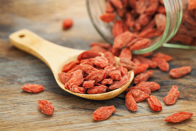 Bacche di Goji rosse su cucchiaio di legno. Superfood salutare e antiossidante.