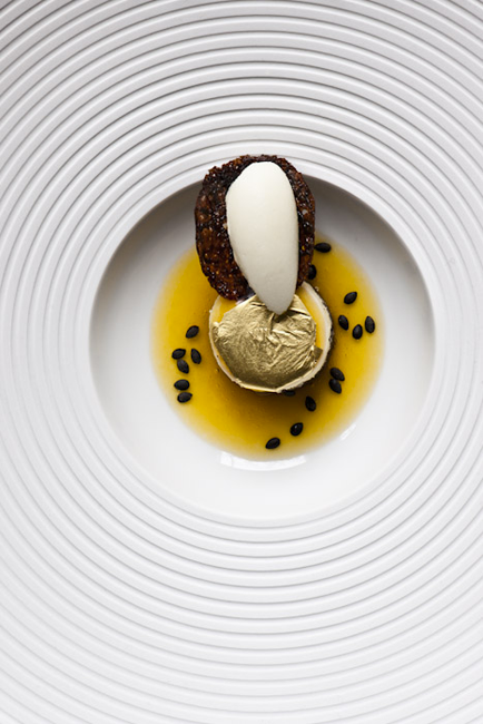 Dessert gourmet con gelato, foglia d'oro e semi neri. Piatto di alta cucina.