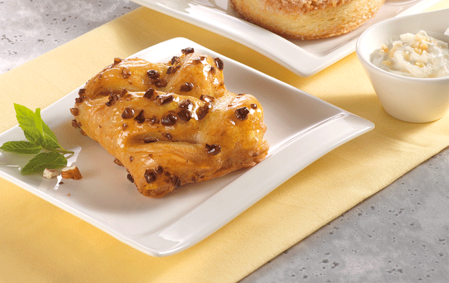 Dolce alla cannella con noci su piatto bianco. Pasticceria artigianale, colazione golosa.