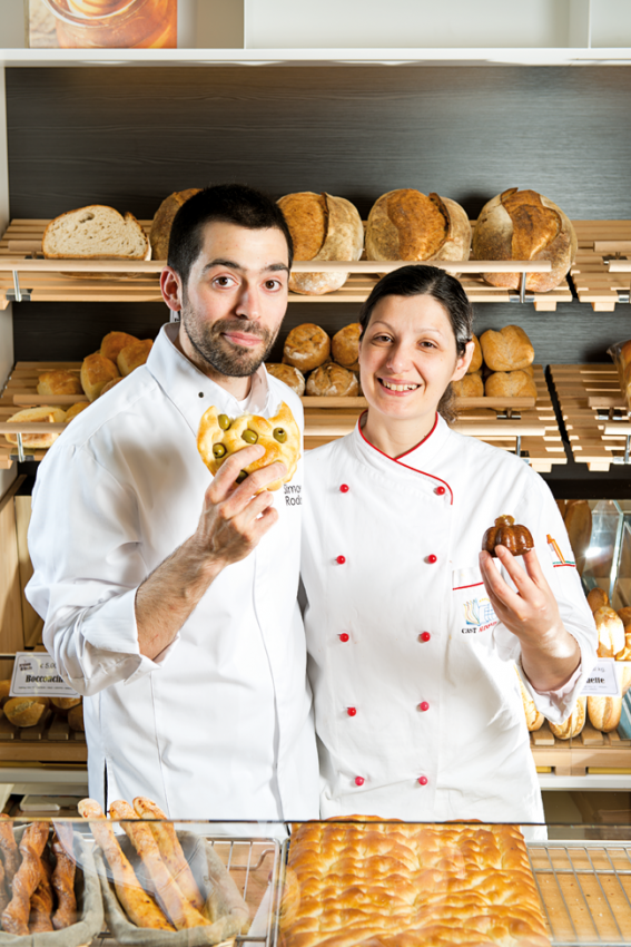 Ritratto di panettieri sorridenti con pane artigianale. Panificio locale.