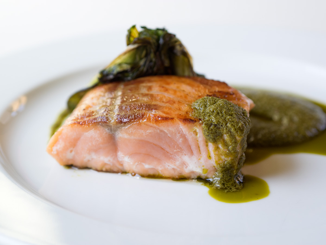 Filetto di salmone grigliato con salsa verde e verdure. Piatto gourmet di pesce.