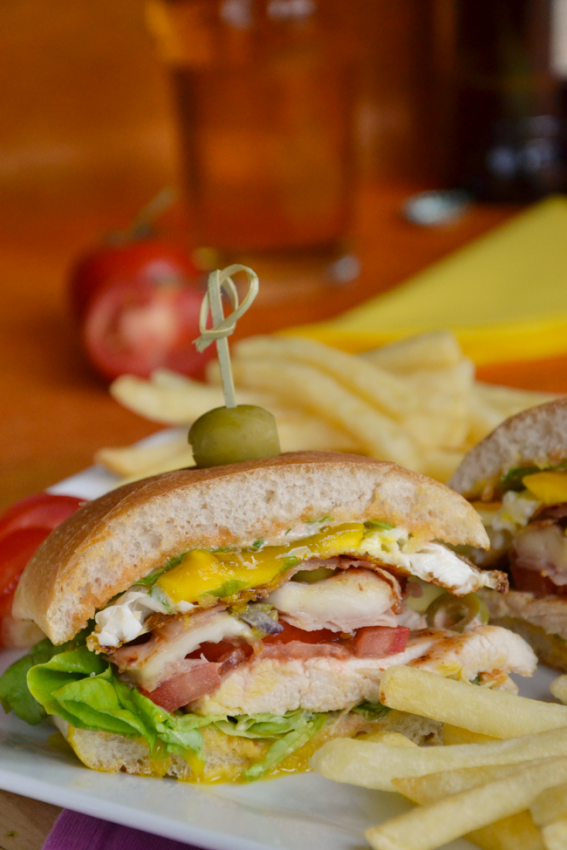 Chivito di pollo uruguaiano con patatine fritte. Panino gourmet con carne, insalata e pomodoro. Ricetta chivito di pollo.