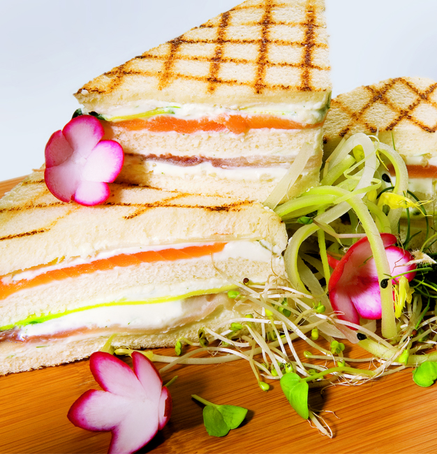 Mini tramezzini triangolari con salmone, formaggio fresco e ravanelli. Snack sfizioso.