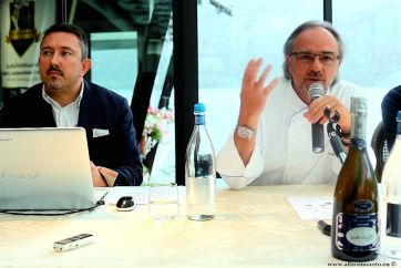 Claudio e Marco Sacco, chef stellato, durante evento. Bottiglia vino e microfono. Cucina italiana.