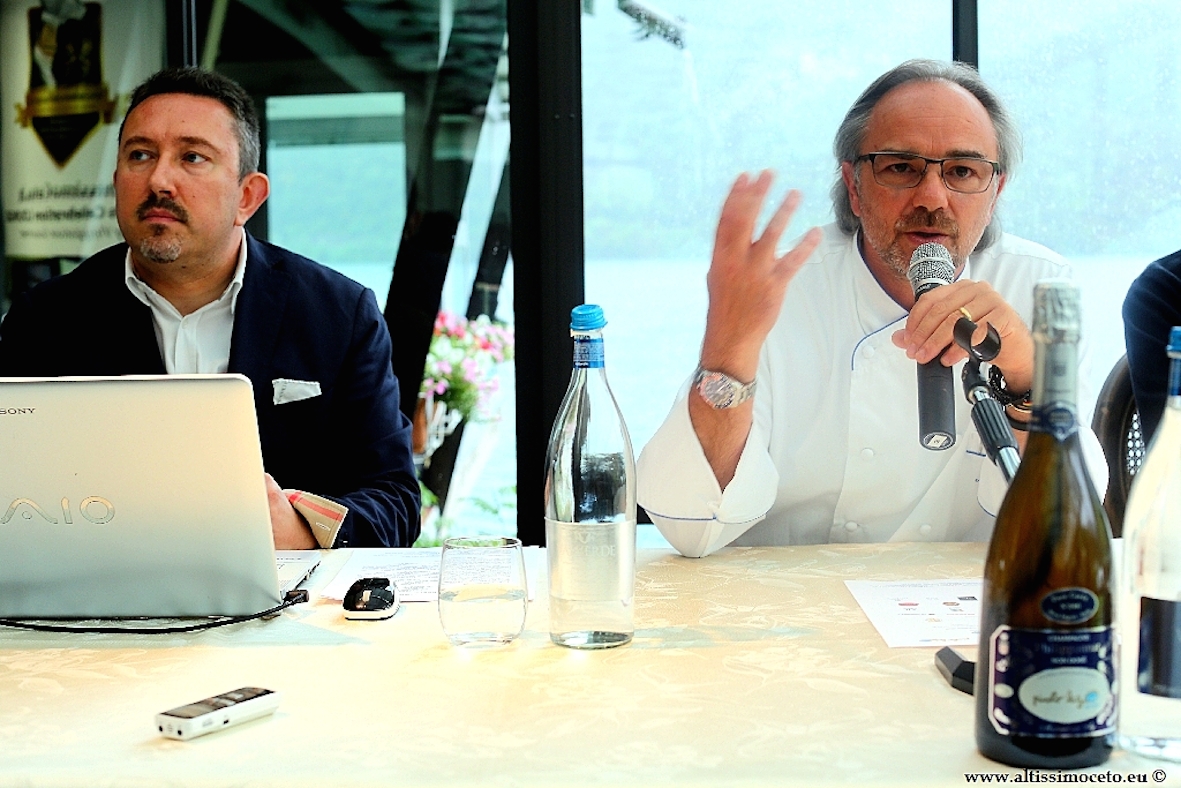Claudio e Marco Sacco, chef stellato, durante evento. Bottiglia vino e microfono. Cucina italiana.
