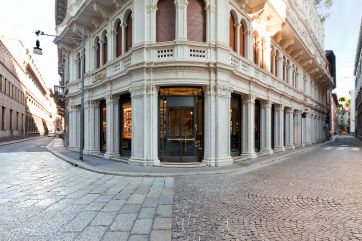 Esterno di edificio storico a Milano. Architettura con colonne e pavimentazione in pietra.