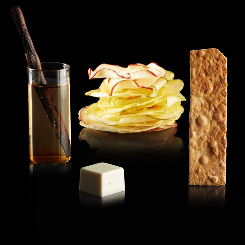 Strudel di mele gourmet: chips di mela, salsa alla vaniglia, croccante. Dessert elegante su fondo nero.