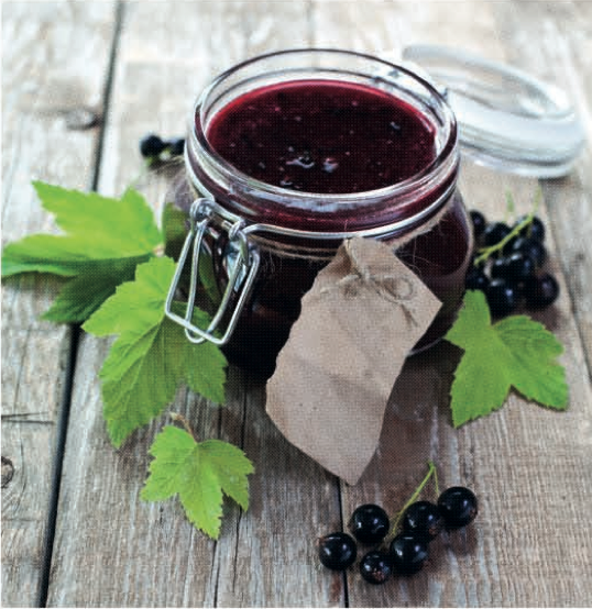 Marmellata di ribes nero fatta in casa in barattolo di vetro su tavolo di legno.