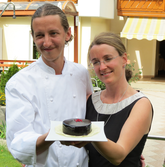 Chef con moglie e torta al cioccolato. Coppia sorridente, dessert delizioso.