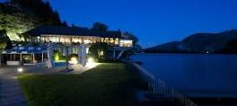 Hotel di lusso illuminato sul lago di notte. Ristorante elegante con vista.