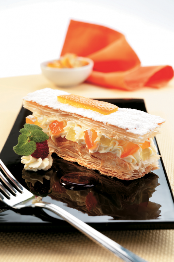 Millefoglie di formaggi freschi con frutta, dolce italiano. Piatto elegante con forchetta.