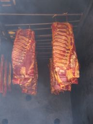 Affumicatura tradizionale: costine di maiale affumicate appese. Specialità gastronomica, sapore intenso.