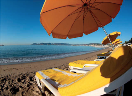 Spiaggia assolata con ombrelloni gialli e lettini. Relax estivo in riva al mare.