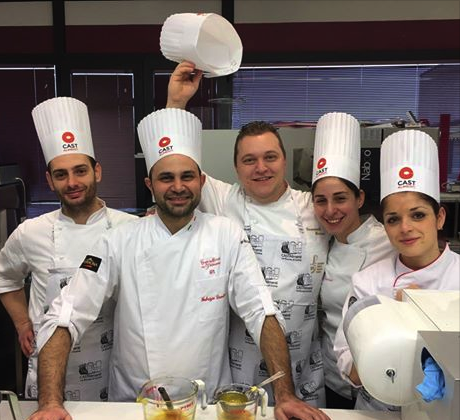Gruppo di chef sorridenti con toque bianca. Formazione professionale in cucina, CAST Alimenti, arte culinaria italiana.