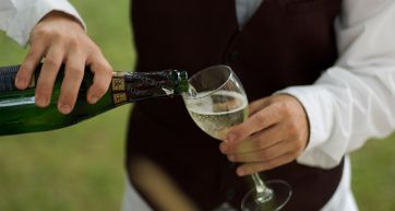 Versando Prosecco in un bicchiere. Bottiglia di vino frizzante, brindisi e celebrazione.