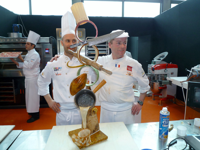 Chef pasticceri a Sigep con scultura di cioccolato. Mostra dolciaria, arte bianca, pasticceria artigianale.