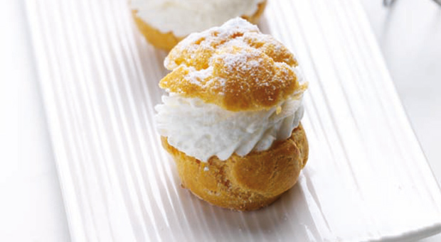 Bignè alla panna spolverato con zucchero a velo. Pasticceria fresca.