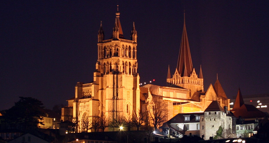 Cattedrale di Losanna illuminata di notte. Architettura gotica svizzera, torri e guglie. Turismo a Losanna.