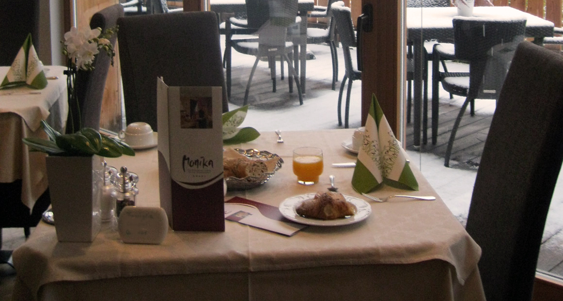 Colazione invernale al ristorante Monika. Croissant, succo d'arancia e pane fresco. Neve fuori.
