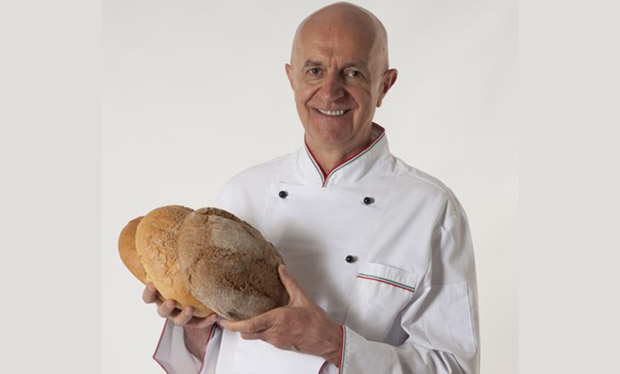 Chef italiano sorridente con pane fatto in casa. Pane a lievitazione naturale, artigianale.