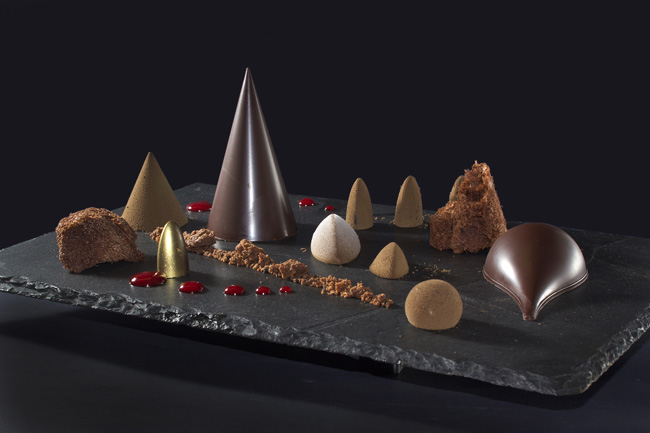 Dolci al cioccolato artistici su ardesia. Dessert creativi con forme geometriche e gocce rosse. Ricetta fregula dolce.