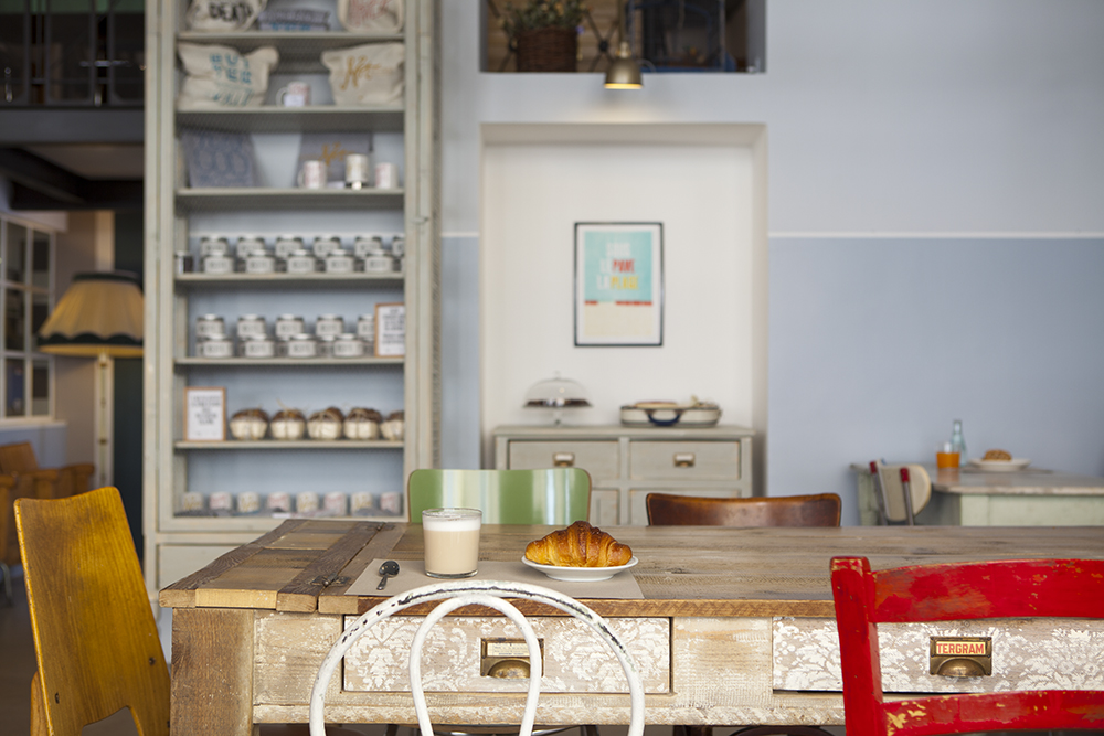 Interno di caffetteria vintage. Tavolo in legno con croissant e latte macchiato. Arredamento retrò, atmosfera accogliente.