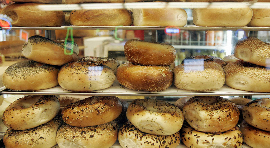 Assortimento di bagel freschi in vetrina. Panini con semi di sesamo e papavero. Ottimi per colazione o brunch.
